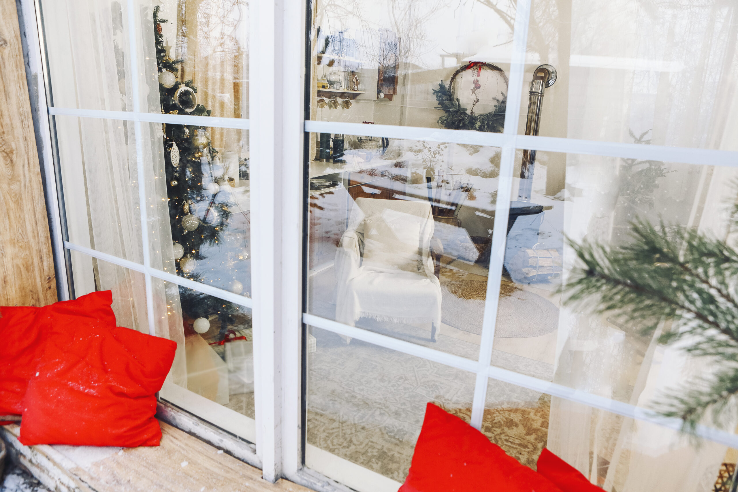 Cozy house with big windows and decorated Christmas tree. Patio at snowy winter evening. Holiday concept